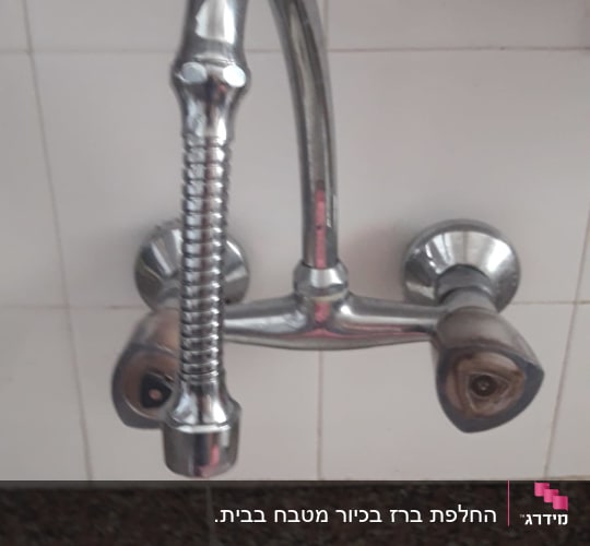 ברז מתכת עם ידית כפולה על קיר קרמיקה